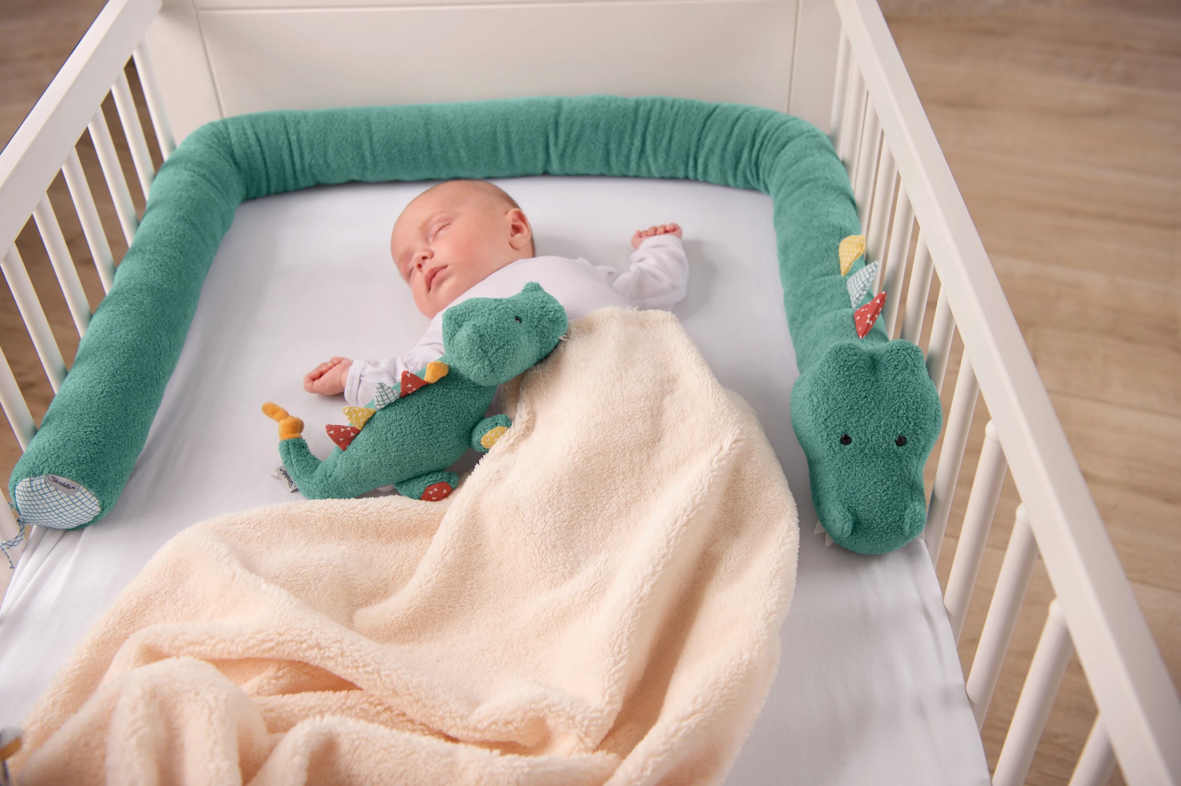 Baby in einem Gitterbett liegend, mit einem Krokodil als Kuscheltier